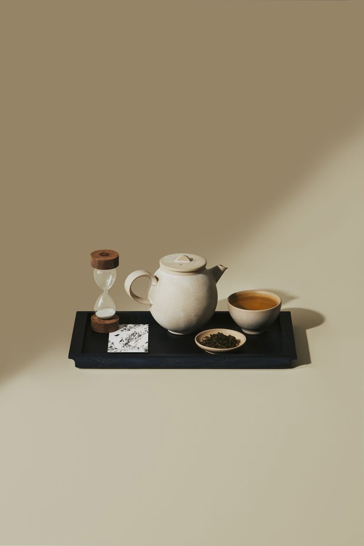 Witte theepot en kopje op een zwart dienblad