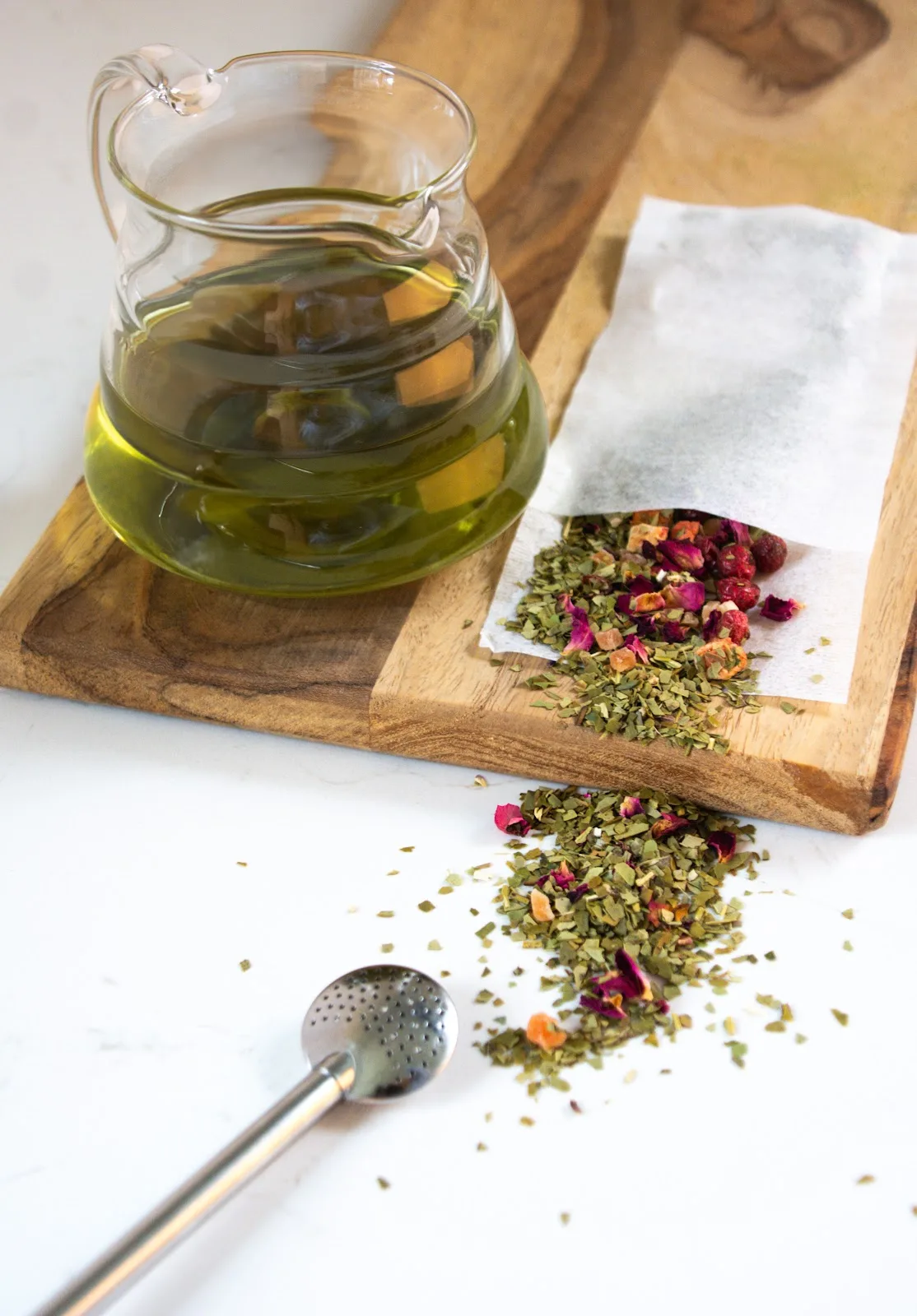 Hoopje losse yerba mate met een bombilla naast een glazen kan mate